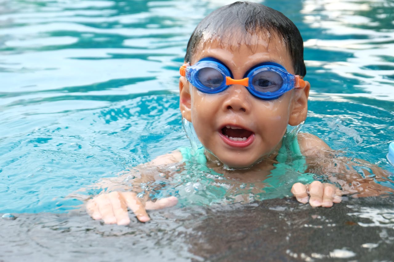 who-we-are Young child playing and swimming in a pool, enjoying the water.